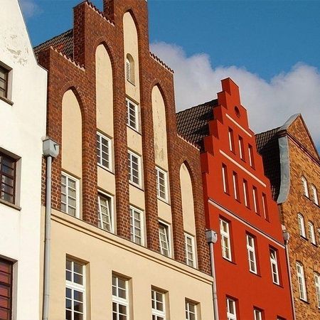 Eine Reihe traditioneller europäischer Treppengiebelhäuser vor blauem Himmel