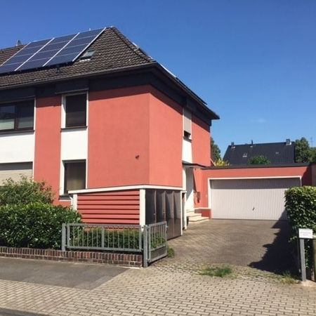 Zweistöckiges rot-weißes Haus mit Sonnenkollektoren auf dem Dach und einer angebauten Garage