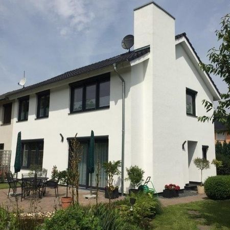 Zweistöckiges weißes Haus mit grünen Fensterläden und einem Garten