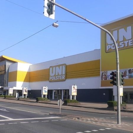Ein gelb-weißes Schaufenster mit der Aufschrift "UNI POLSTER" neben einer Ampel