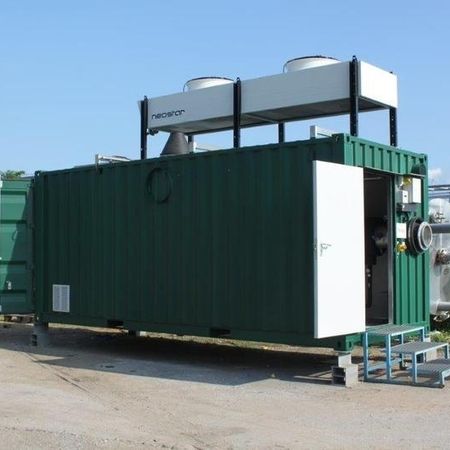 Grüner Industriecontainer mit Ausrüstung und Tanks auf dem Dach, draußen auf Beton