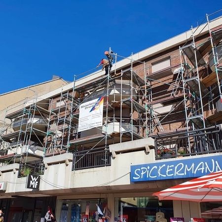 Ein Gebäude, das gerade renoviert wird, mit Gerüsten und Arbeitern unter einem strahlend blauen Himmel.