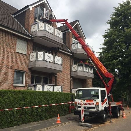 Ein Hubwagen fährt seinen Ausleger in Richtung eines Wohnblocks mit Sicherheitsbarrieren aus.