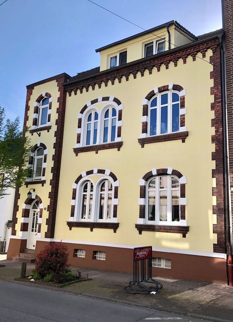 Dreistöckiges Gebäude mit Backsteinakzenten und Bogenfenstern.
